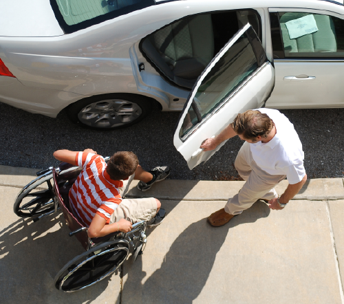 Driver opening up a car door for a passenger in a wheelchair