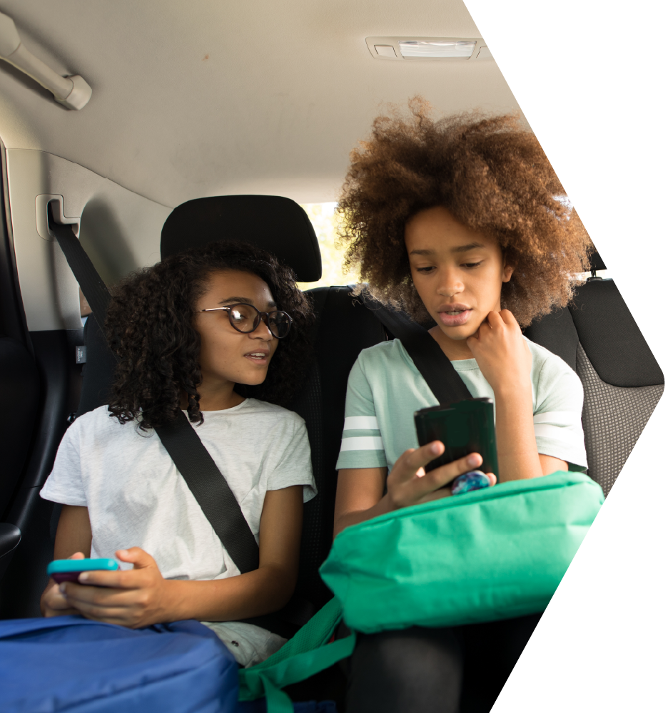 Two students talking to each other in the back seat of a car
