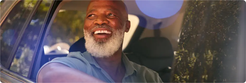 Senior smiling, looking out window of car